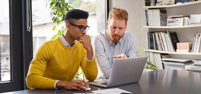 Two people in an office working together at a laptop.